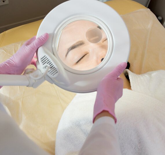 cosmetologist using magnifying lamp FVCNW6E